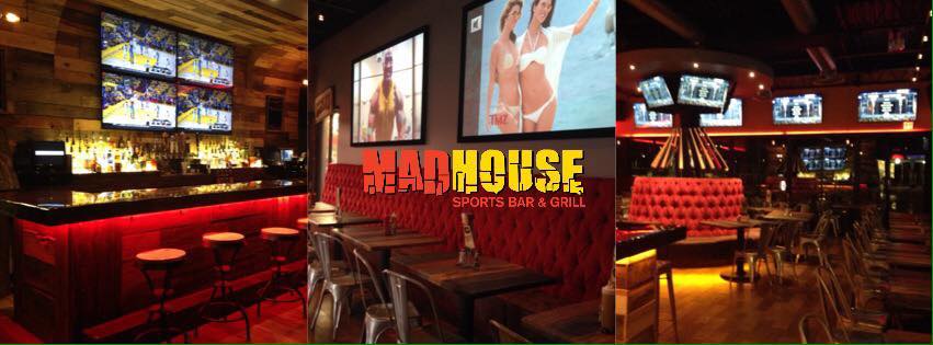 Sports bar with plush red sofas, high stools and multiple TV sets at Madhouse Sports Bar & Grill