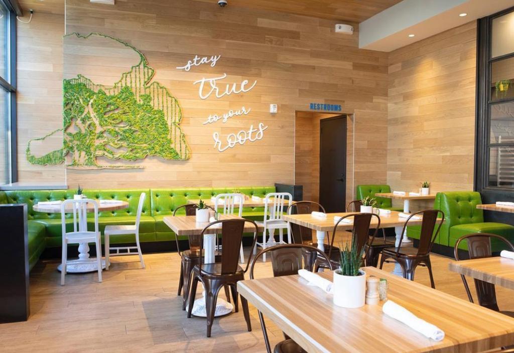 Earth toned restaurant furnished with green, white and brown chairs; wall covered with green and white art at True Food Kitchen