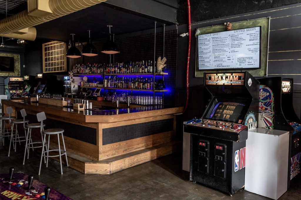 Rustic style bar with high stools and a jukebox at Joystick Gamebar
