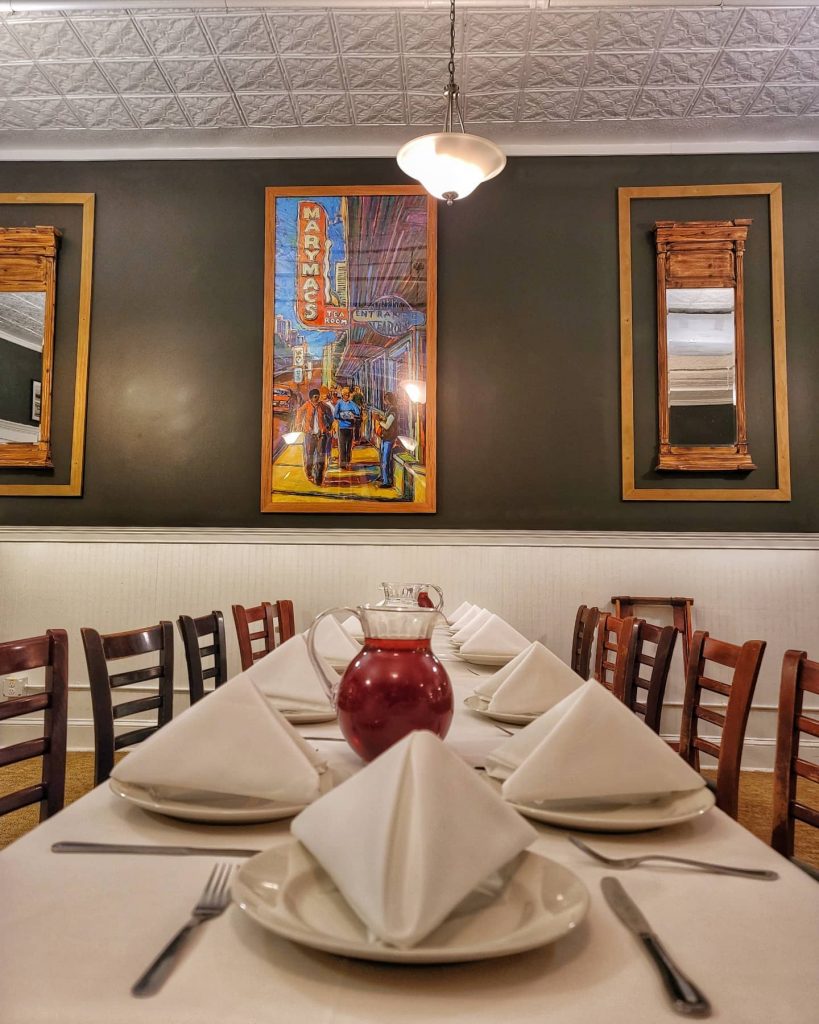 Restaurant with formally arranged tables set against dark gray walls decorated with paintings at Mary Mac's Tea Room