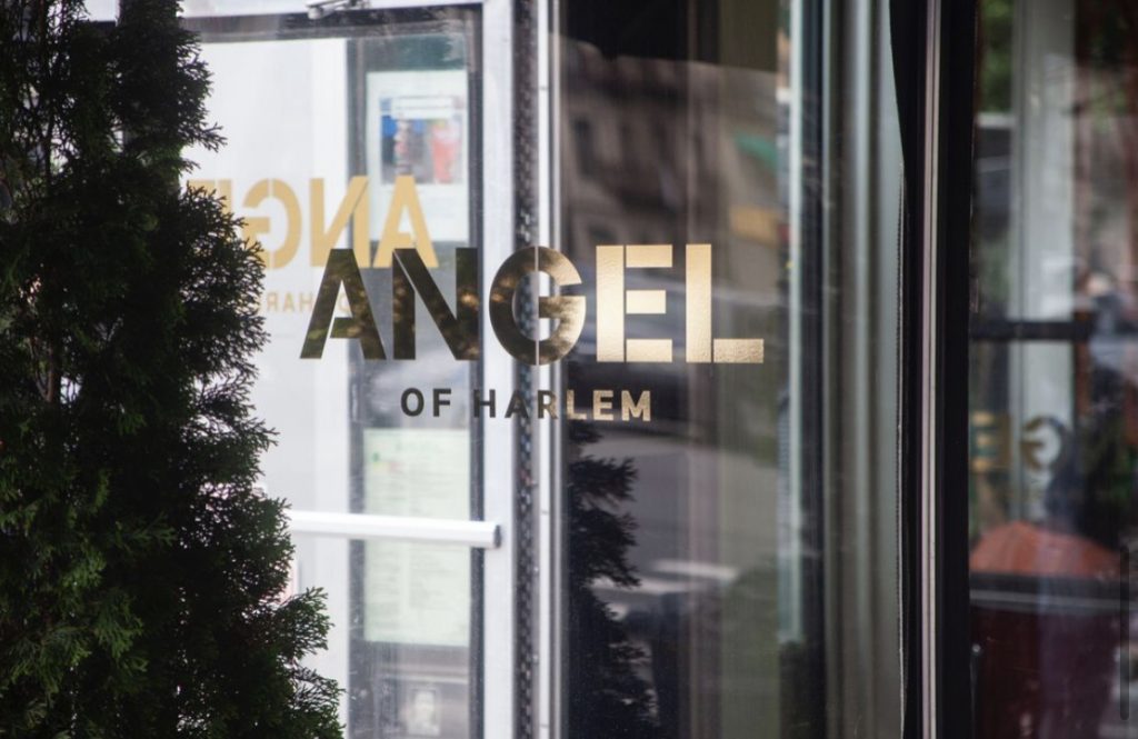 Christmas tree beside window with the Angel of Harlem sign.