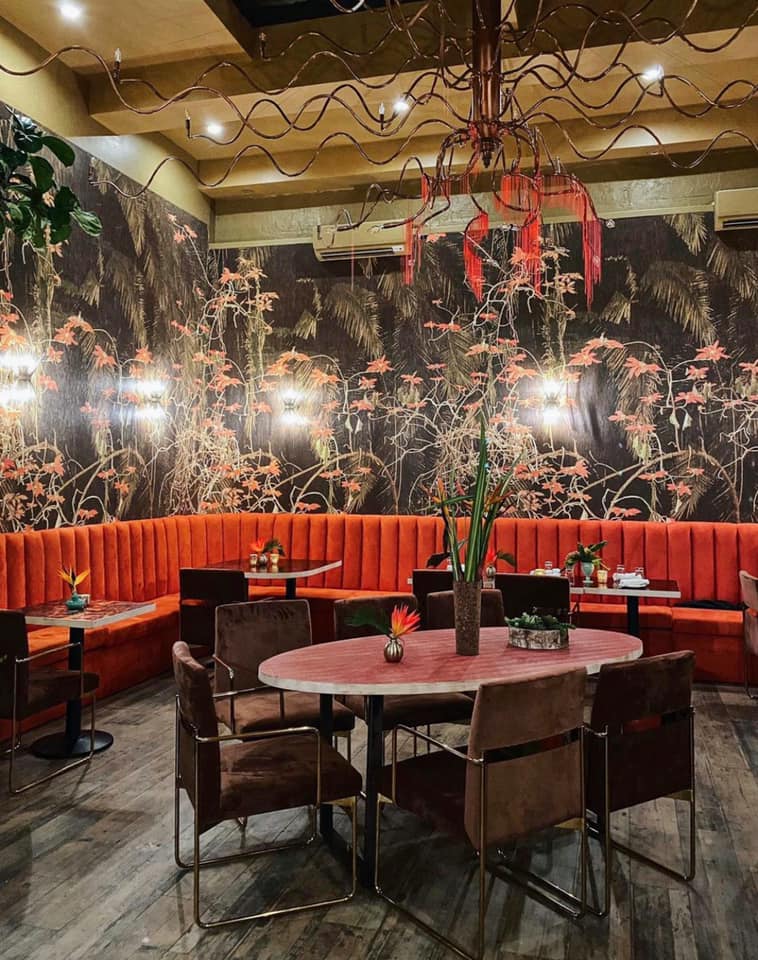 Colorful restaurant decorated with flowers in vases and floral wall paintings at Kokomo