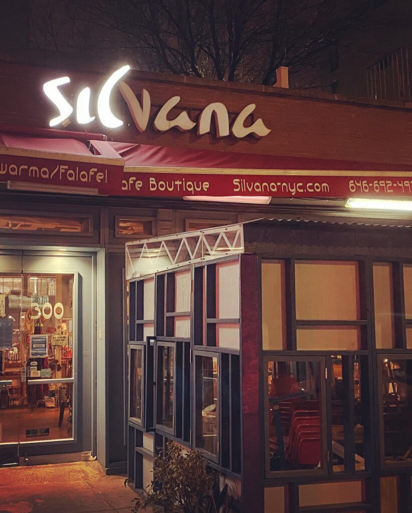 Outdoor view of restaurant with the Silvana logo lighted above a red awning at Silvana